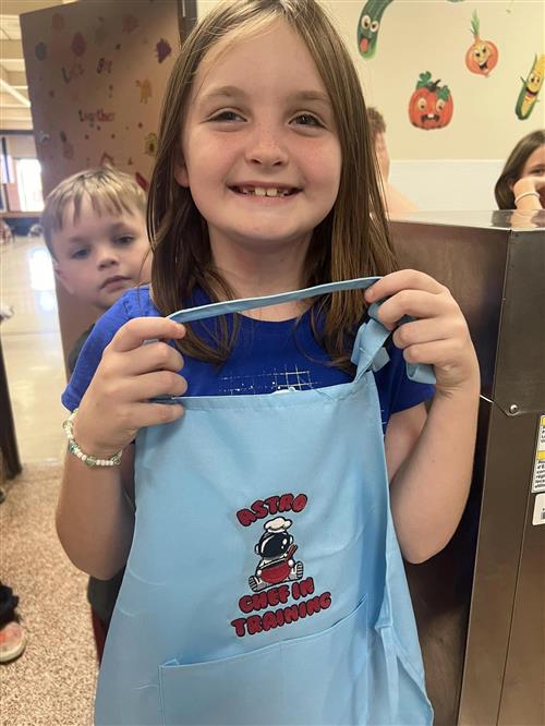 A student holds up her apron for the Rocket Fuel Club.