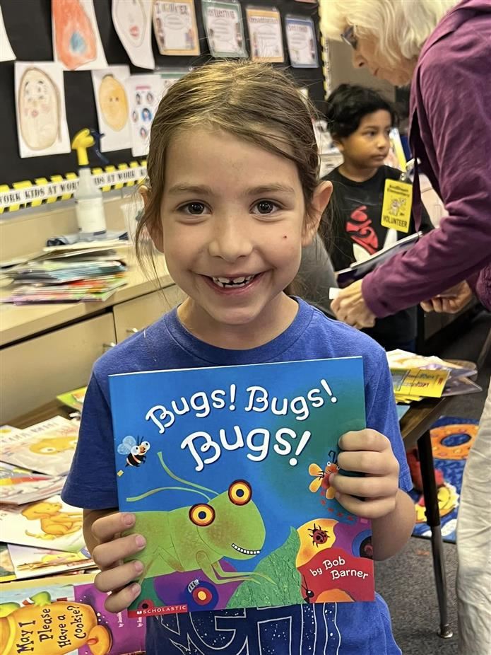Little girl holding book during guest reader event 