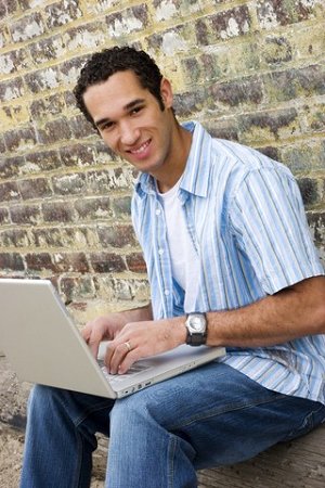 Boy on laptop in front of brick wall