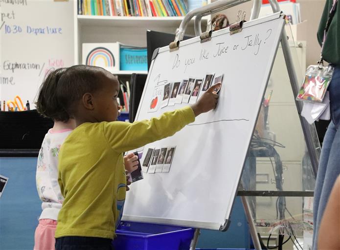  Image of student putting a polaroid on a whiteboard. 
