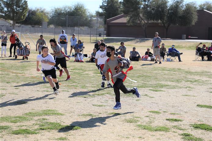  Flag football player runs down the field with the football and others chasing after him